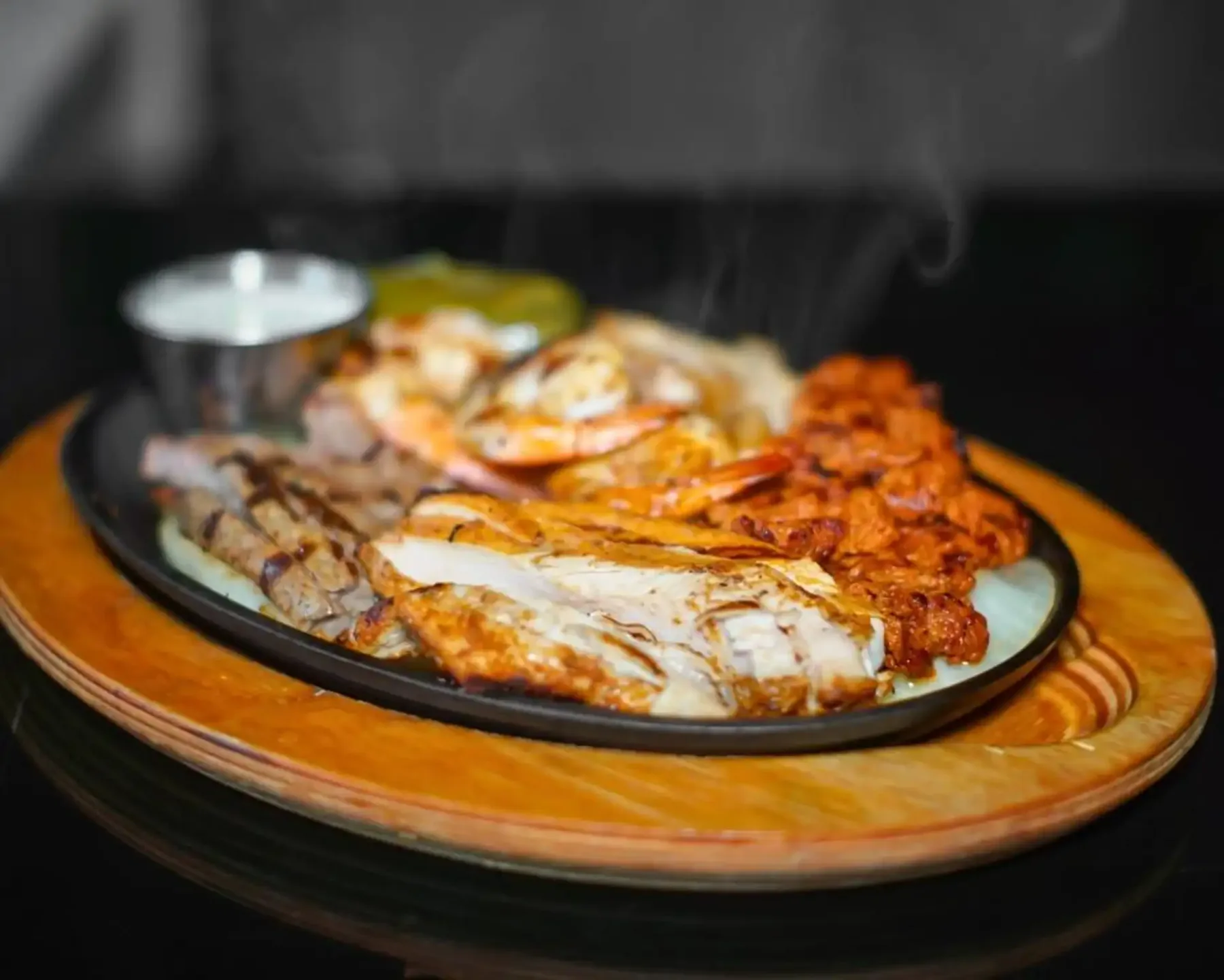 Sizzling Mas Amigos fajitas — grilled chicken, steak, and shrimp on a hot wooden platter